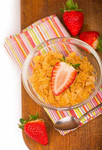 Bol de yaourt avec des fraises fraîches tranchées et des flocons de maïs secs Concept traditionnel de petit-déjeuner de flocons de maïs Concept de saine alimentation Alimentation et santé