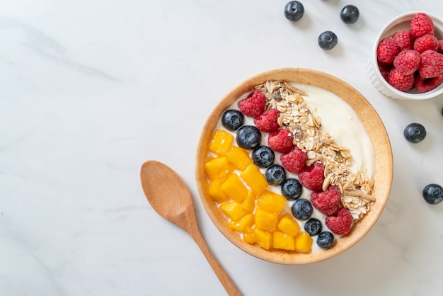 bol de yogourt fait maison avec framboise, myrtille, mangue et granola - style alimentaire sain