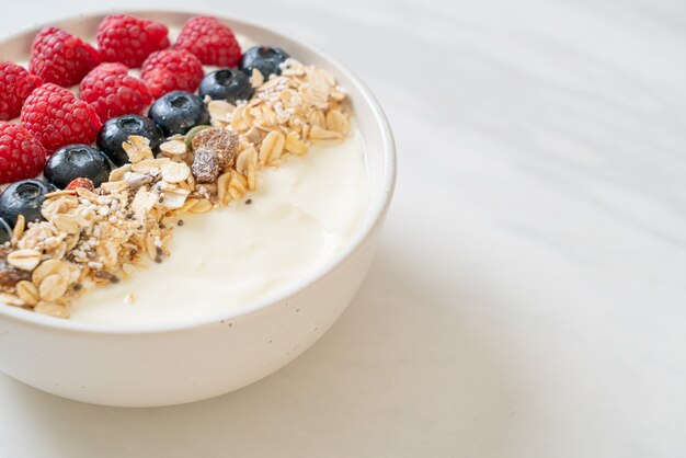 bol de yogourt fait maison avec framboises, myrtilles et granola - style alimentaire sain