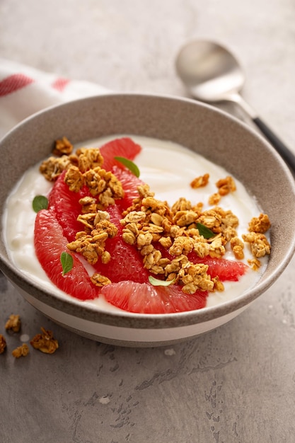 Un bol de yogourt avec des tranches de pamplemousse et du granola