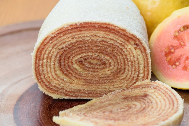 Bolo de rolo sur une planche de bois à côté de goyaves