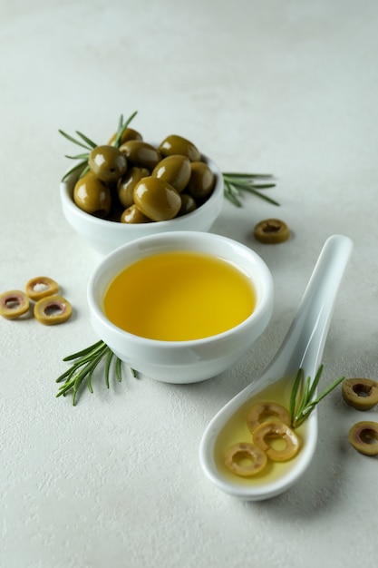 Bols aux olives et huile sur fond texturé blanc