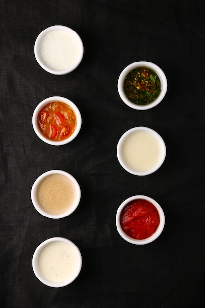 Bols de diverses sauces sur la vue de dessus de table noire. ensemble de sauces