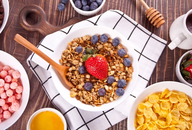 Photo bols avec fraise, boules de maïs sucré au chocolat, muesli et flocons de maïs aux baies. céréales de petit-déjeuner délicieuses et saines. vue de dessus.