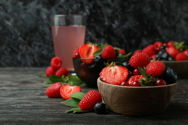 Bols avec mélange de baies et jus sur table en bois