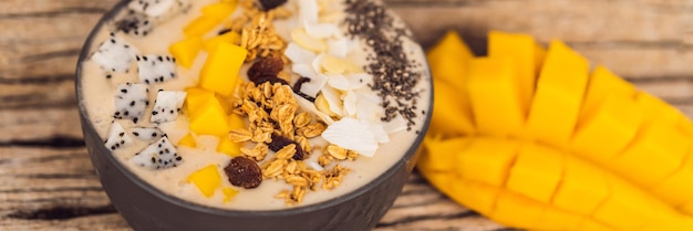 Bols de smoothie à base de mangue banane granola noix de coco râpée fruit du dragon graines de chia et menthe sur