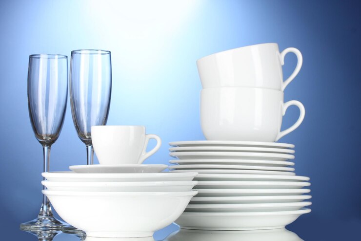 Photo des bols vides, des assiettes, des tasses et des verres sur fond bleu