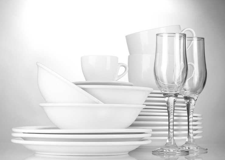 Photo des bols vides, des assiettes, des tasses et des verres sur un fond gris.