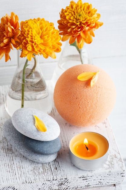 Bombe de bain aromatique en composition spa avec fleurs orange et galets. Arrangement d'aromathérapie, nature morte zen avec des bougies allumées