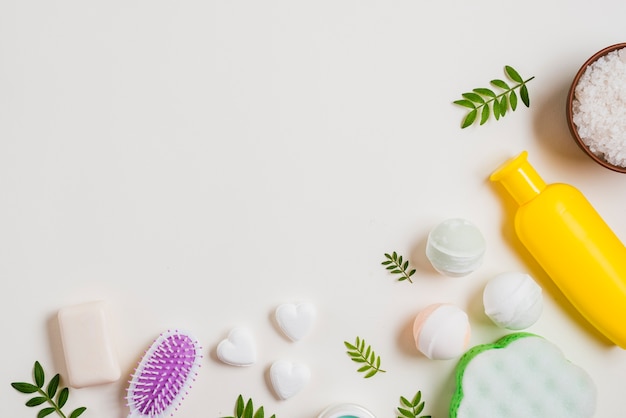 Bombe de bain; savon en forme de coeur; sel et brosse à cheveux avec une bouteille de cosmétiques sur fond blanc