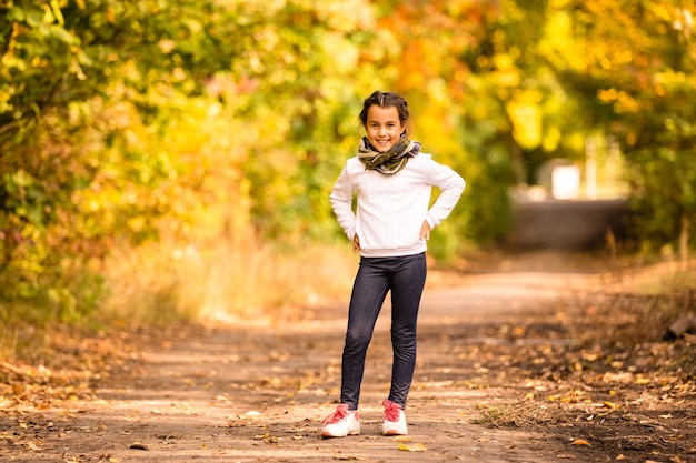 Bon automne ! Petite fille douce jouant avec des feuilles dans un parc en automne. Copiez l'espace, les feuilles tombent.