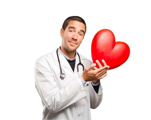 Bon docteur tenant un coeur de jouet sur fond blanc