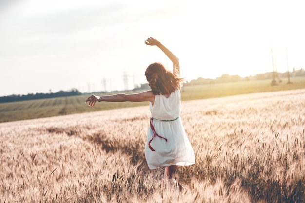 Bon été et liberté. Belle fille au champ de blé par une journée ensoleillée