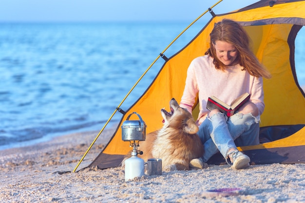 Bon week-end au bord de la mer - fille avec un chien dans une tente sur la plage à l'aube. Paysage ukrainien à la mer d'Azov, Ukraine