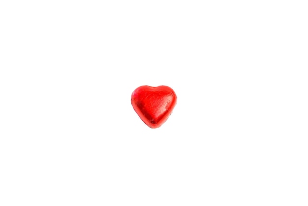 Bonbon au chocolat en forme de coeur enveloppé dans du papier d'aluminium rouge sur fond blanc