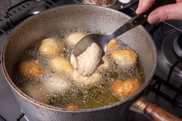 Bonbon brésilien appelé bolinho de Chuva, mis à frire dans une poêle avec de l'huile, mise au point sélective.