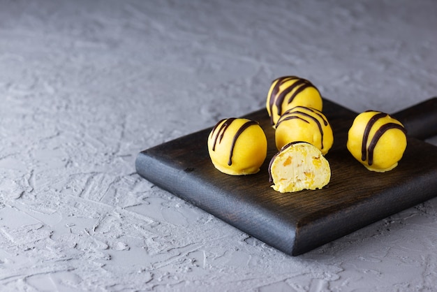 Bonbons à l'ananas et à la mangue au chocolat jaune sur une planche en bois sans gluten et sans lactose