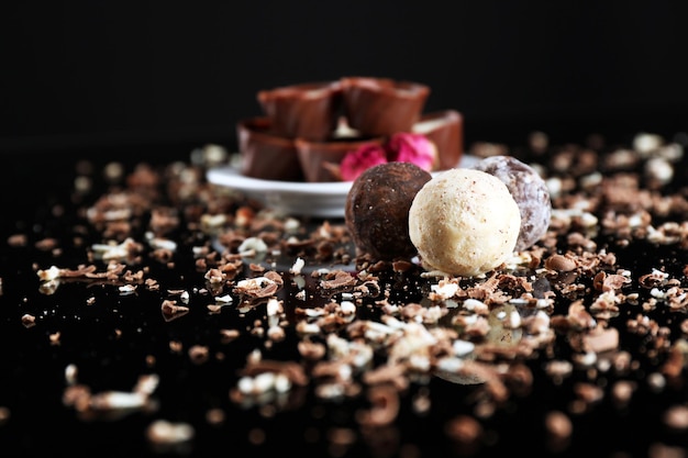 Bonbons au chocolat assortis avec des flocons sur fond noir