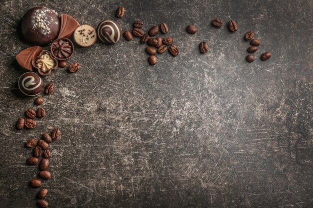 Bonbons au chocolat délicieux avec des grains de café sur fond de table gris