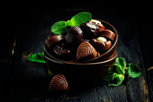 Bonbons au chocolat et feuilles de menthe sur fond sombre mise au point sélective