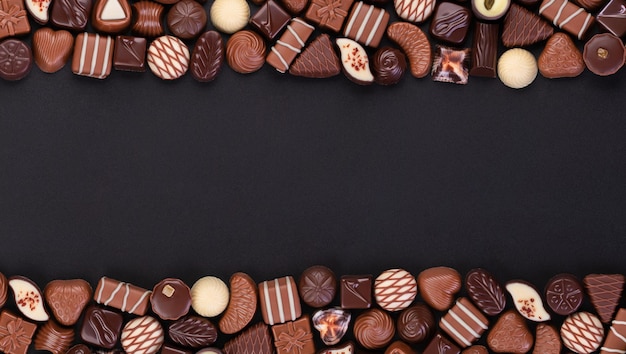 Bonbons au chocolat sur fond de tableau noir diverses pralines et truffes avec espace vide