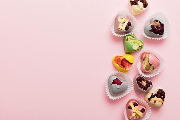 bonbons au chocolat en forme de cœur avec des fruits et des noix sur un fond coloré vue supérieure avec de l'espace pour le texte concept de vacances