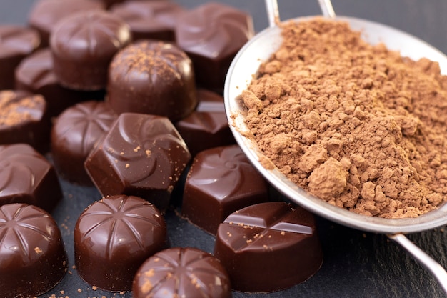Bonbons au chocolat sur une surface noire, poudre de cacao. photo sombre, humeur.