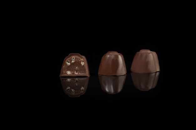 Bonbons au chocolat sur une surface sombre avec reflet. Remplissage de noix et de fruits. Espace de copie.