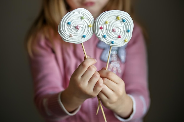 Bonbons sur un bâton dans les mains des enfants Le concept de boulangerie de fête des bonbons