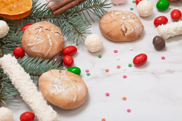 Bonbons et biscuits avec des branches d'arbres de Noël sur fond de marbre blanc