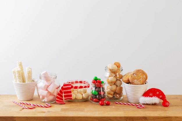 Bonbons et biscuits de Noël dans des bocaux sur une étagère en bois sur fond blanc