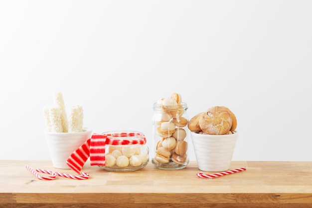 Bonbons et biscuits de Noël dans des bocaux sur une étagère en bois sur fond blanc