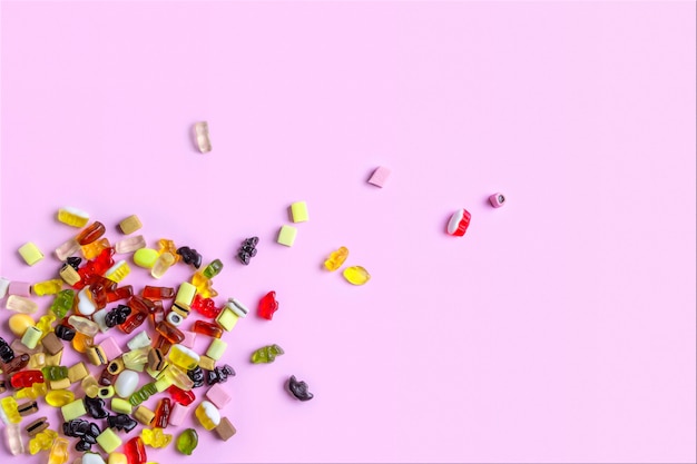 Bonbons de bonbons colorés sur une surface rose