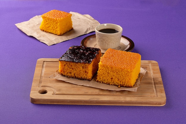 Bonbons de boulangerie sur une planche en bois avec un gâteau aux carottes et du pain français en arrière-plan à côté d'une tasse o