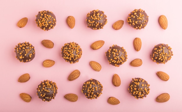 Bonbons boule chocolat caramel aux amandes d'affilée sur une surface rose pastel