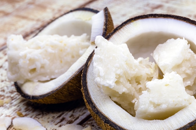 Bonbons brésiliens à la noix de coco, appelés "cocada", à l'intérieur de deux noix de coco ouvertes, sur fond de bois blanc