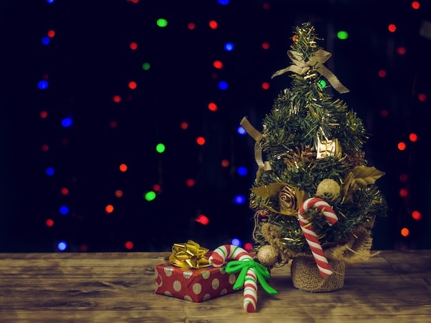 Bonbons et cadeaux de Noël sur une table en bois près d'un sapin.