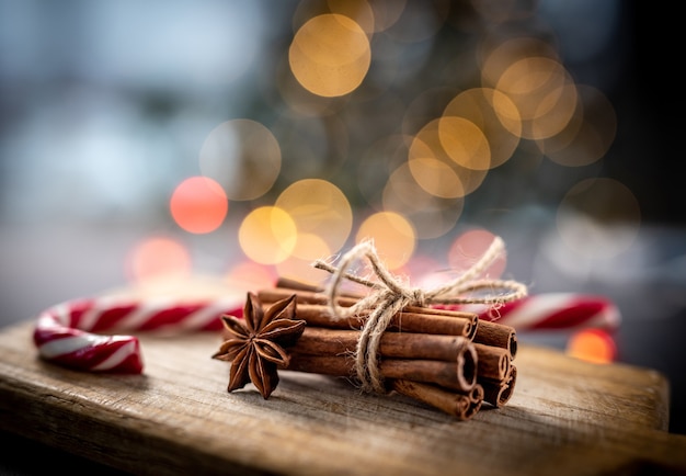 Bonbons de canne de Noël à côté de bâtons de cannelle et d'anis étoilé sur l'éclairage de la guirlande