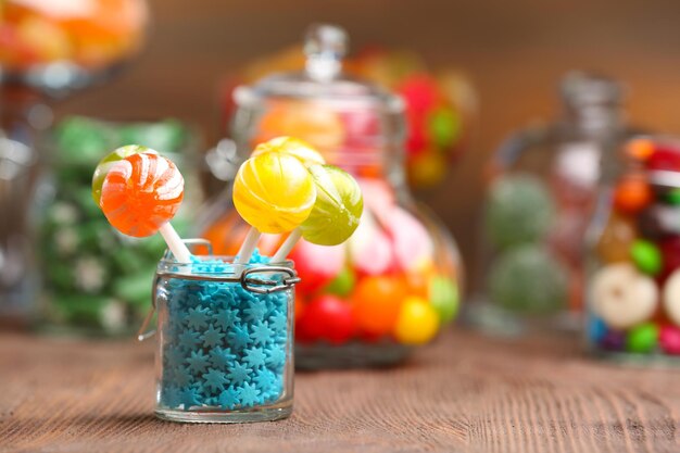 Photo bonbons colorés dans des bocaux sur table sur fond de bois