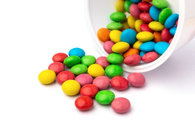 Bonbons colorés dans un conteneur ouvert isolé sur une surface blanche