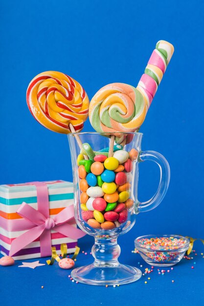 Photo des bonbons colorés dans une tasse sur la table sur un fond clair grands sucettes tourbillonnantes concept créatif d'un pot plein de délicieux bonbons du magasin de bonbons