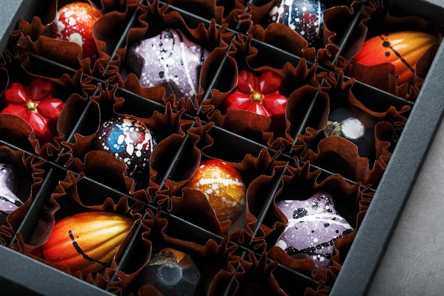 Bonbons colorés de différentes formes faits à la main à partir de chocolat dans une boîte