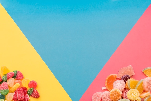 Photo bonbons colorés de gelée sucrée sur le fond triangulaire jaune et rose