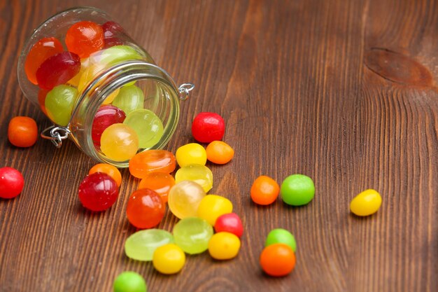 Bonbons colorés en pot sur fond de bois