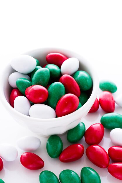 Bonbons colorés rouges, verts et blancs sur fond blanc.