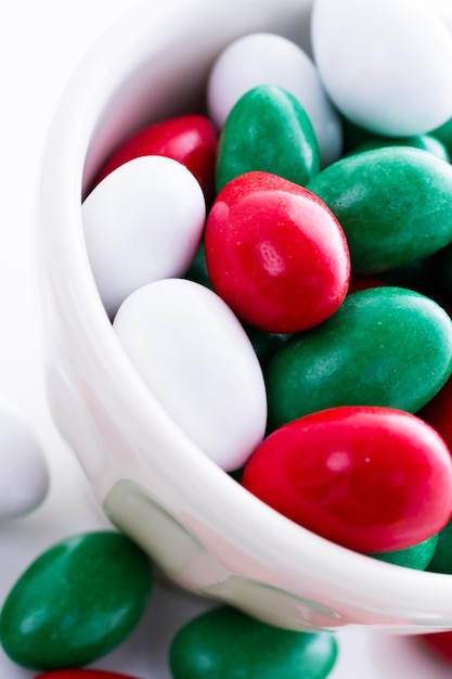 Bonbons colorés rouges, verts et blancs sur fond blanc.