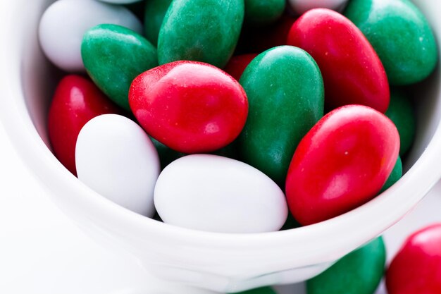 Bonbons colorés rouges, verts et blancs sur fond blanc.