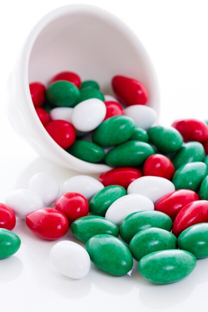 Bonbons colorés rouges, verts et blancs sur fond blanc.