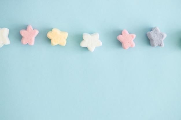 Bonbons de couleur douce sous forme d'étoiles sur fond bleu