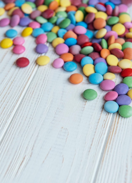 Bonbons dragée multicolores sur une surface en bois blanc
